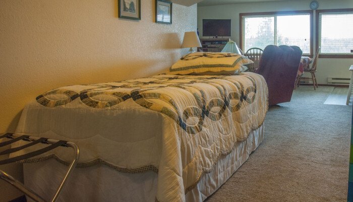 Cozy bedroom with quilted bed, chair, and window view