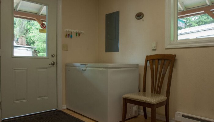 Small room with white door, chest freezer, and chair