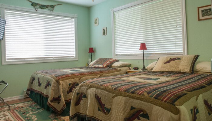 Bright twin bedroom with wildlife quilts and green walls.