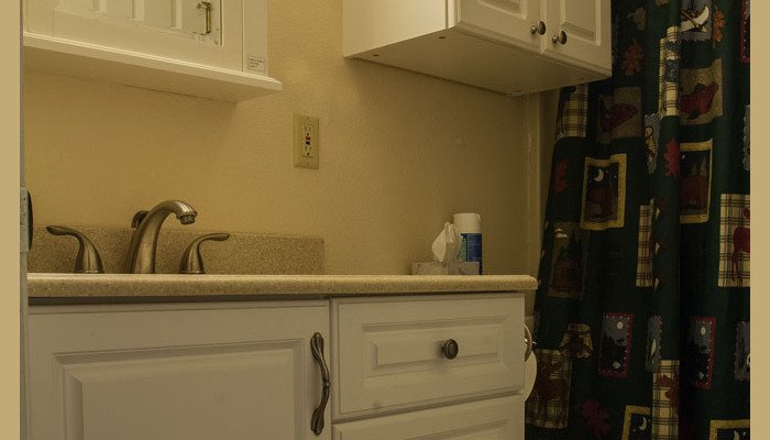 Well-lit bathroom with white cabinets and patterned curtain